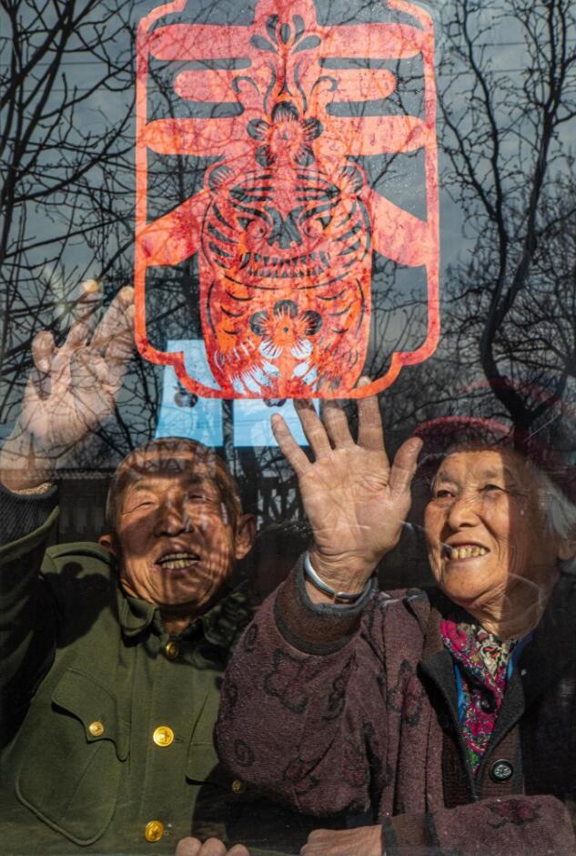臘月里，霍州市師莊鄉(xiāng)馮南垣村村民師榮光(左)在災后重建的新家里貼窗花。(霍州市委宣傳部供圖)