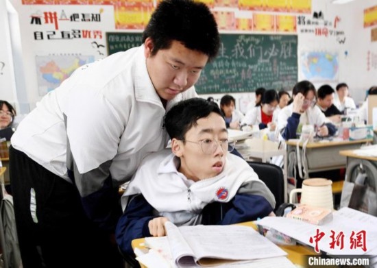 朱金祥(左)把鐘華強(qiáng)放到課堂座位上后，都要把他擺正好，確認(rèn)安全后才回到自己的座位上。 卓忠偉 攝