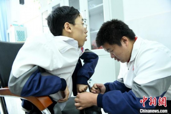 江西省南康中學(xué)北校區(qū)的高三學(xué)生朱金祥(右)正在給鐘華強(qiáng)(左)系好鞋帶。 卓忠偉 攝
