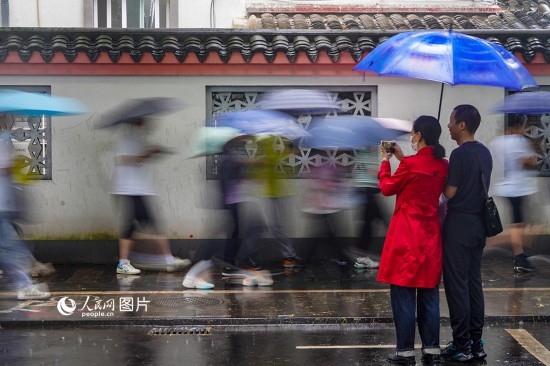 6月7日，在浙江省2023年普通高校招生考試鎮(zhèn)海中學(xué)考點(diǎn)，家長(zhǎng)冒雨目送子女進(jìn)入考場(chǎng)。人民網(wǎng) 章勇濤攝