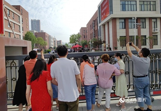 6月7日，武漢市第三中學(xué)考點(diǎn)，考生進(jìn)場(chǎng)后，家長(zhǎng)在柵欄外用手機(jī)拍攝自己的孩子。人民網(wǎng)記者 郭婷婷攝