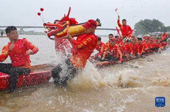 6月22日，在湖南省岳陽市湘陰縣湘江臨資口水域，參加龍舟賽的隊(duì)員接“龍頭”下水。