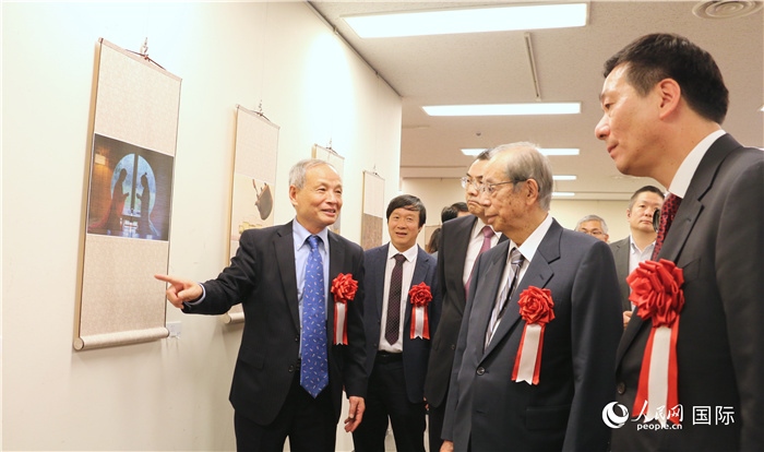 “湖州印象”攝影展主創(chuàng)、世界華人攝影協(xié)會(huì)副會(huì)長(zhǎng)馮學(xué)敏向吳江浩大使、福田康夫前首相等嘉賓介紹展出作品。（人民網(wǎng) 許可攝）