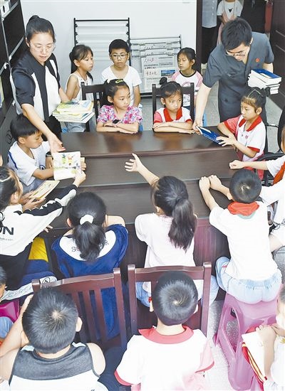  圖④：法院干警為留守兒童發(fā)放暑假讀物。