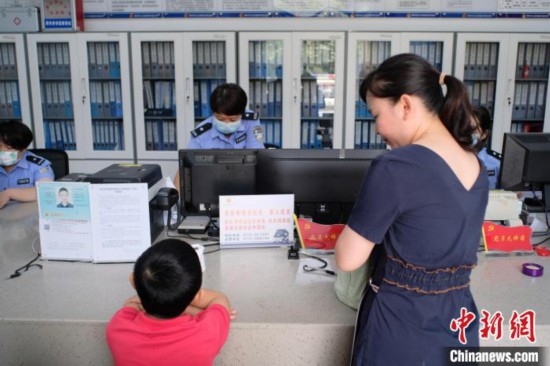 圖為一名家長正在辦證窗口前為孩子申領居民身份證。劉俊聰 攝
