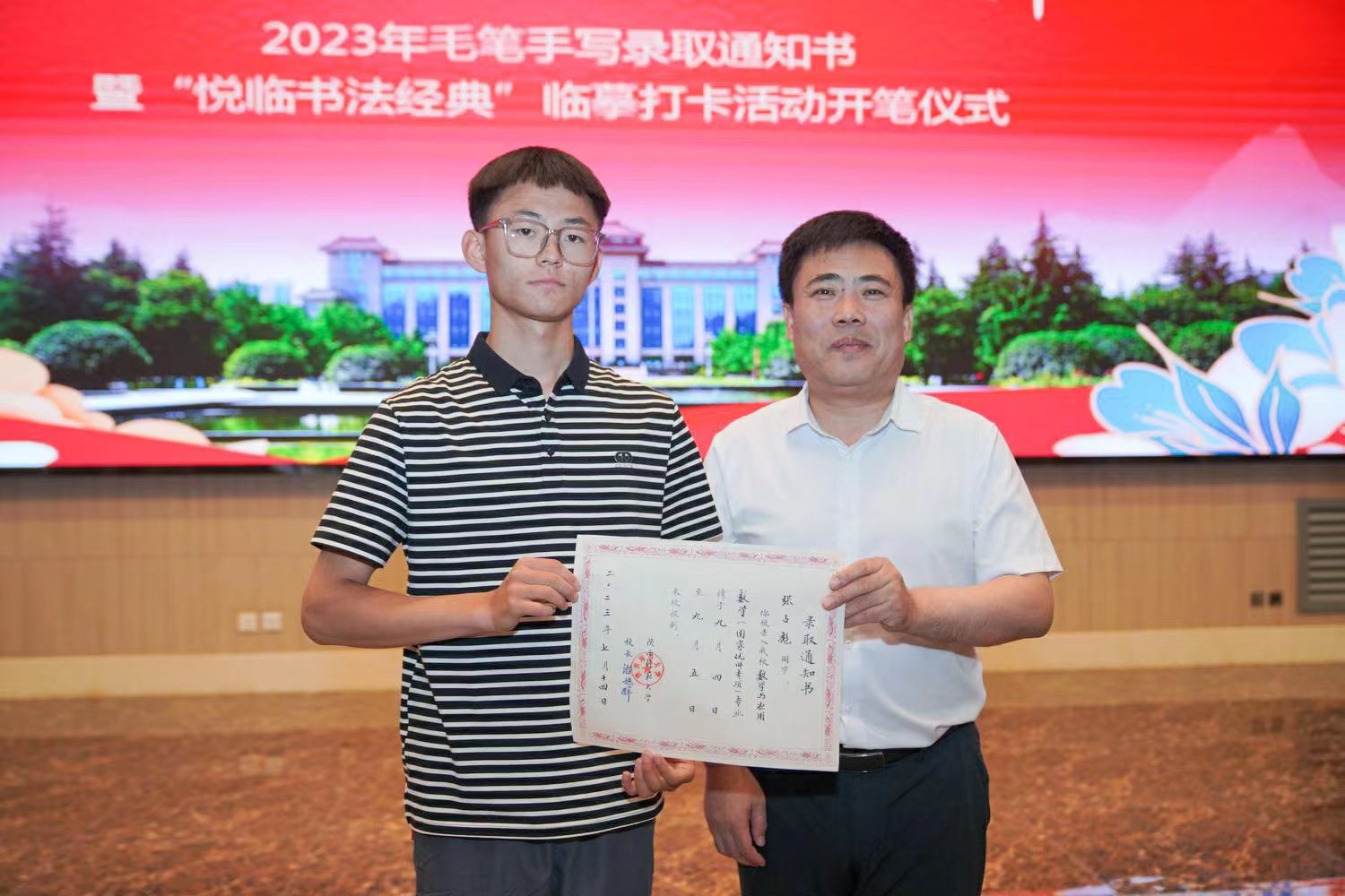 陜西師范大學黨委書記李忠軍為2023級新生代表張占彪同學發(fā)放錄取通知書。校方供圖