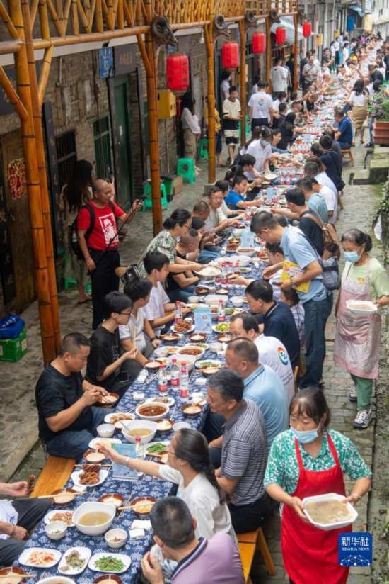 7月29日，在重慶市綦江區(qū)安穩(wěn)鎮(zhèn)，人們在“苗家伏羊節(jié)”上吃長桌宴。新華社記者 唐奕 攝