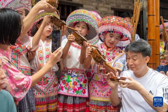 7月29日，在重慶市綦江區(qū)安穩(wěn)鎮(zhèn)，當?shù)鼐用裨凇懊缂曳蚬?jié)”上用傳統(tǒng)習俗向游客表達祝福。新華社記者 唐奕 攝