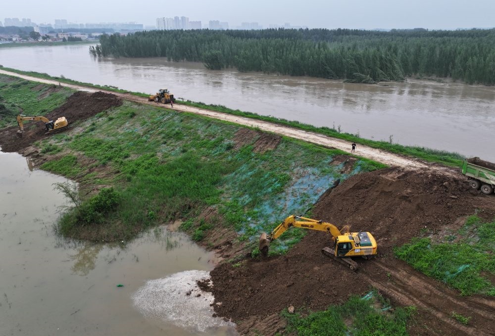 工人操作機(jī)械在白溝河左堤白溝新城高橋村段進(jìn)行除險(xiǎn)加固作業(yè)（8月4日攝，無人機(jī)照片）。新華社記者 朱旭東 攝