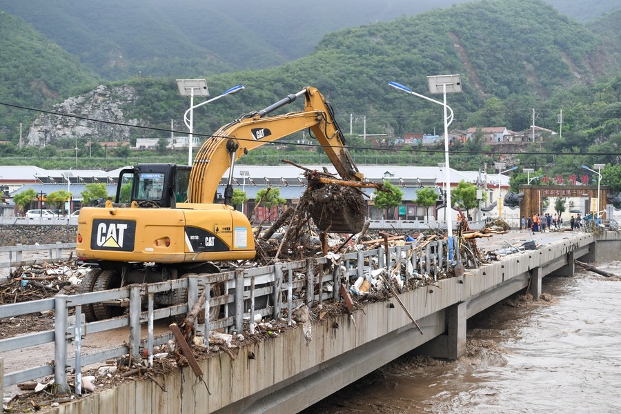 8月1日，在北京市門頭溝區(qū)水峪嘴村村口，一臺(tái)挖掘機(jī)在清理阻斷橋梁交通的雜物。目前該條道路已經(jīng)疏通完成。新華社記者 鞠煥宗 攝
