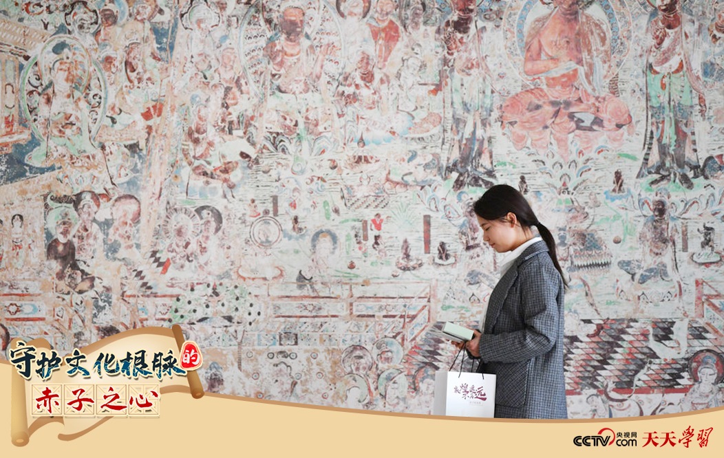 2023年4月25日，敦煌研究院文物數(shù)字化保護(hù)團(tuán)隊(duì)創(chuàng)意營銷人員廖雪婷從一幅高保真復(fù)制壁畫前走過。
