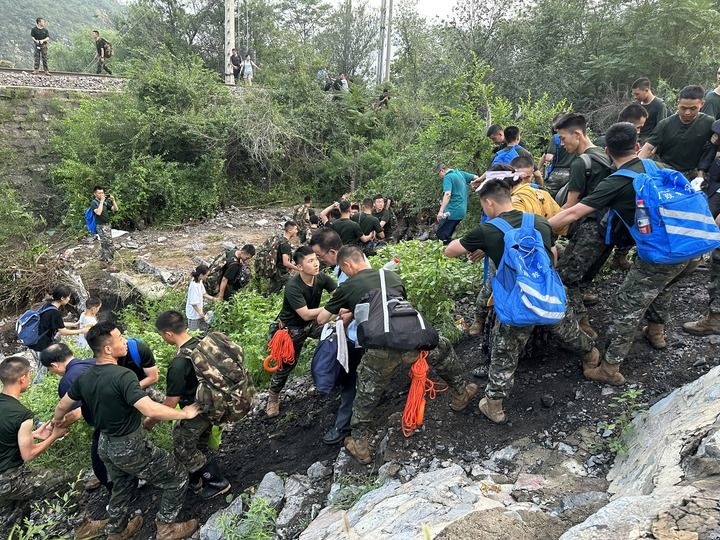 8月2日，Z180次受困列車的旅客在武警北京總隊機動第三支隊官兵的幫助下徒步前往轉(zhuǎn)運客車（手機照片）。新華社記者 王艷剛 攝