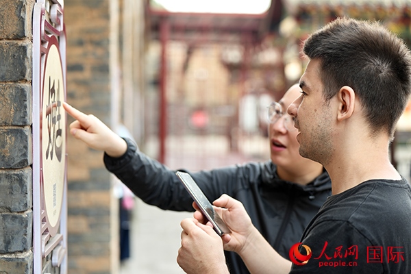 選手安德烈（俄羅斯）在老師指導(dǎo)下學(xué)習(xí)墻壁上張貼的生僻字。人民網(wǎng) 盧鵬宇攝