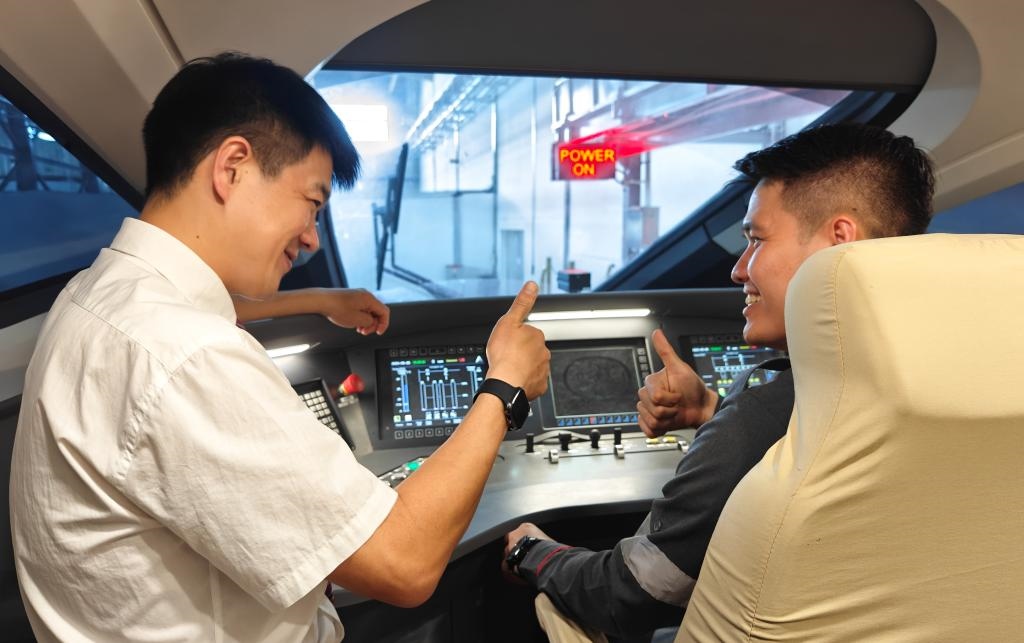 8月25日，在印度尼西亞萬隆的雅萬高鐵德卡魯爾動車所內(nèi)，中國師傅穆振（左）在向印尼火車司機塞蒂亞萬講解動車組出庫前的上電作業(yè)。