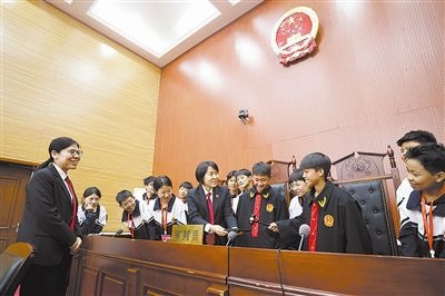 圖③：同學(xué)們穿法袍、敲法槌，爭做“小法官”。