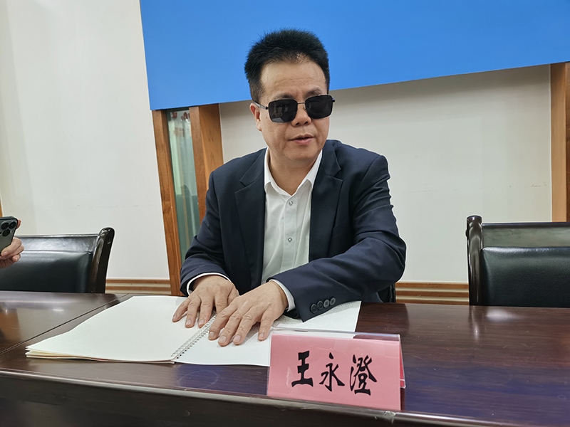 全國人大代表王永澄正在閱讀盲文版代表建議答復(fù)。本報記者 張 璁?dāng)z