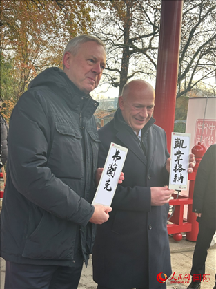 柏林市長韋格納（右）、動物園監(jiān)事會主席布魯克曼（左）手持中國文化中心工作人員現(xiàn)場手書的中文名字。人民網(wǎng)記者 徐馨攝