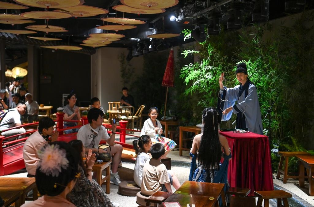 游客在長(zhǎng)安十二時(shí)辰主題街區(qū)觀看唐風(fēng)演藝《大唐曲藝》。新華社記者鄒競(jìng)一 攝