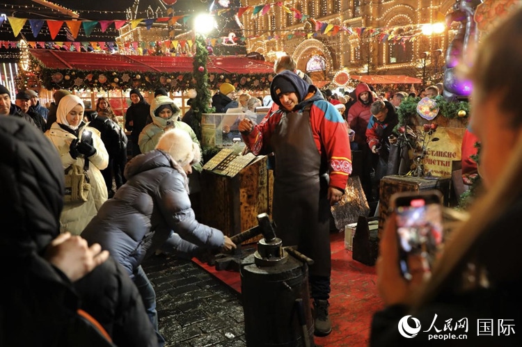 游客在新年集市上體驗(yàn)制作紀(jì)念幣。人民網(wǎng)記者 隋鑫攝