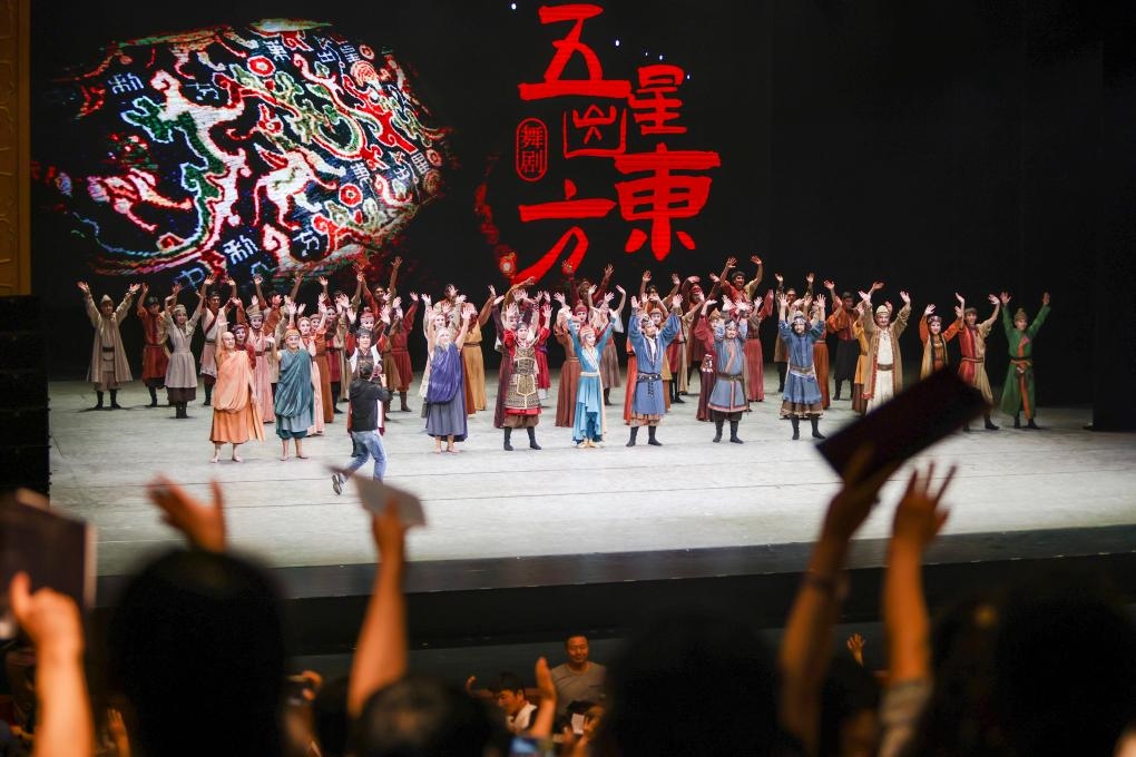 2023年7月31日，新疆和田地區(qū)新玉歌舞團(tuán)在烏魯木齊京劇院演出舞劇《五星出東方》后和觀眾互相揮手致意。這場演出是第六屆中國新疆國際民族舞蹈節(jié)的參演劇目之一，曾榮獲國家“文華獎”等。新華社記者 郝昭 攝