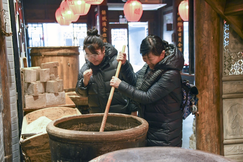 游客在平遙古城東湖老醋坊內(nèi)體驗陳醋發(fā)酵打耙（2022年1月28日攝）。新華社發(fā)（梁生仁攝）