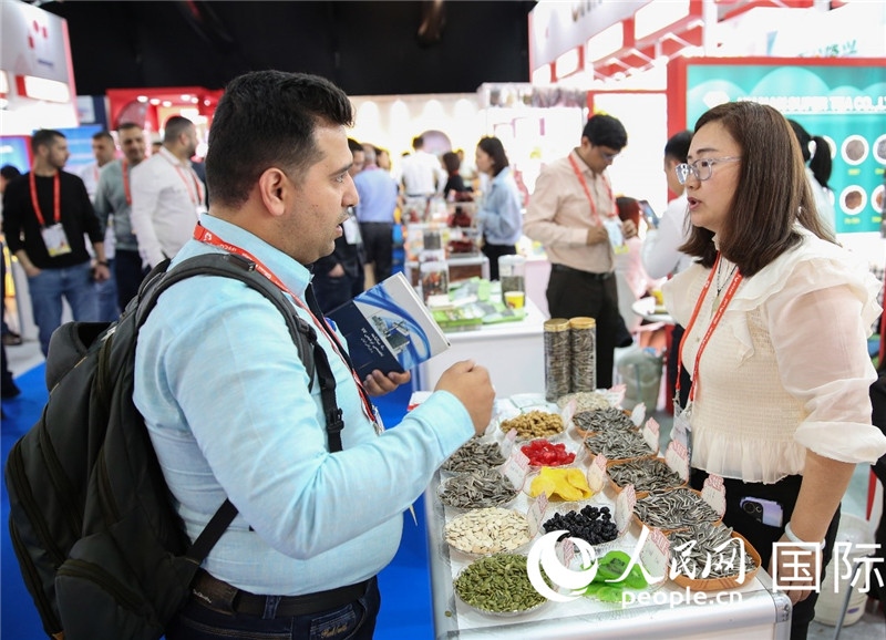圖為一家中國干果參展企業(yè)代表與采購商洽談。人民網 塔里克·易卜拉欣攝
