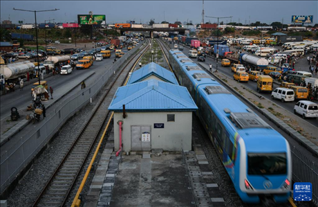 3月4日，在尼日利亞拉各斯，一列輕軌藍線列車行駛至公路交通擁堵路段附近。新華社記者 韓旭 攝