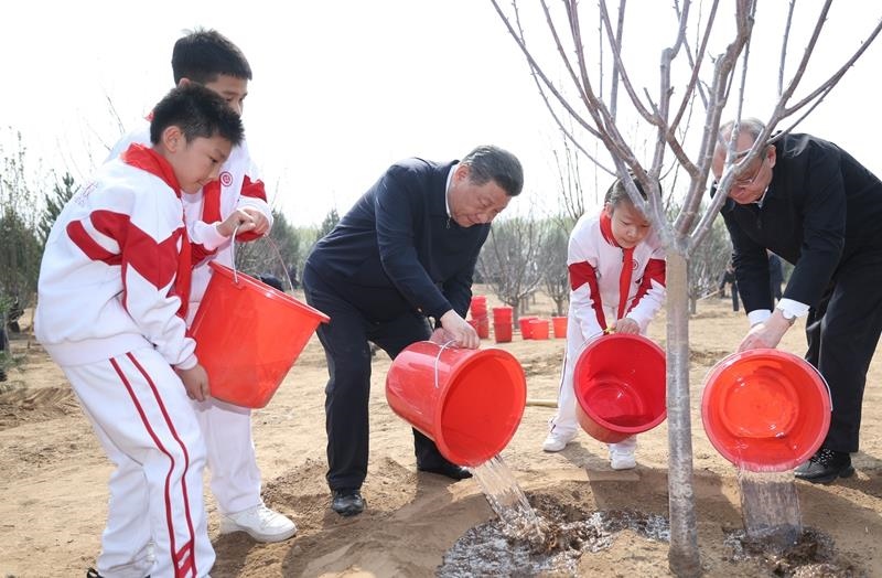 2024年4月3日，習(xí)近平總書記同少先隊(duì)員一起給剛栽下的樹苗澆水。