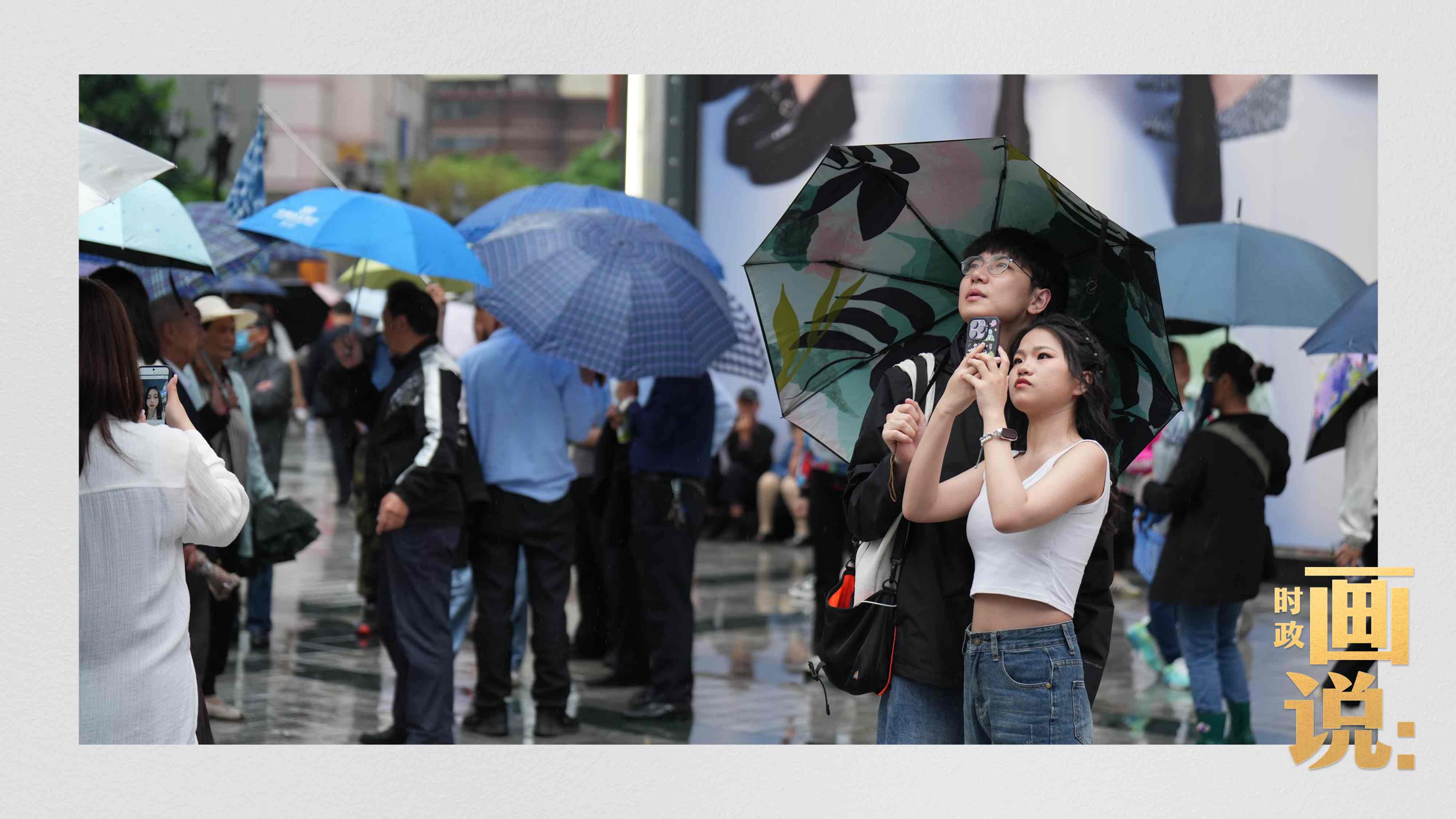 △細(xì)雨中的解放碑步行街，騎在父親肩膀的小女孩好奇張望。