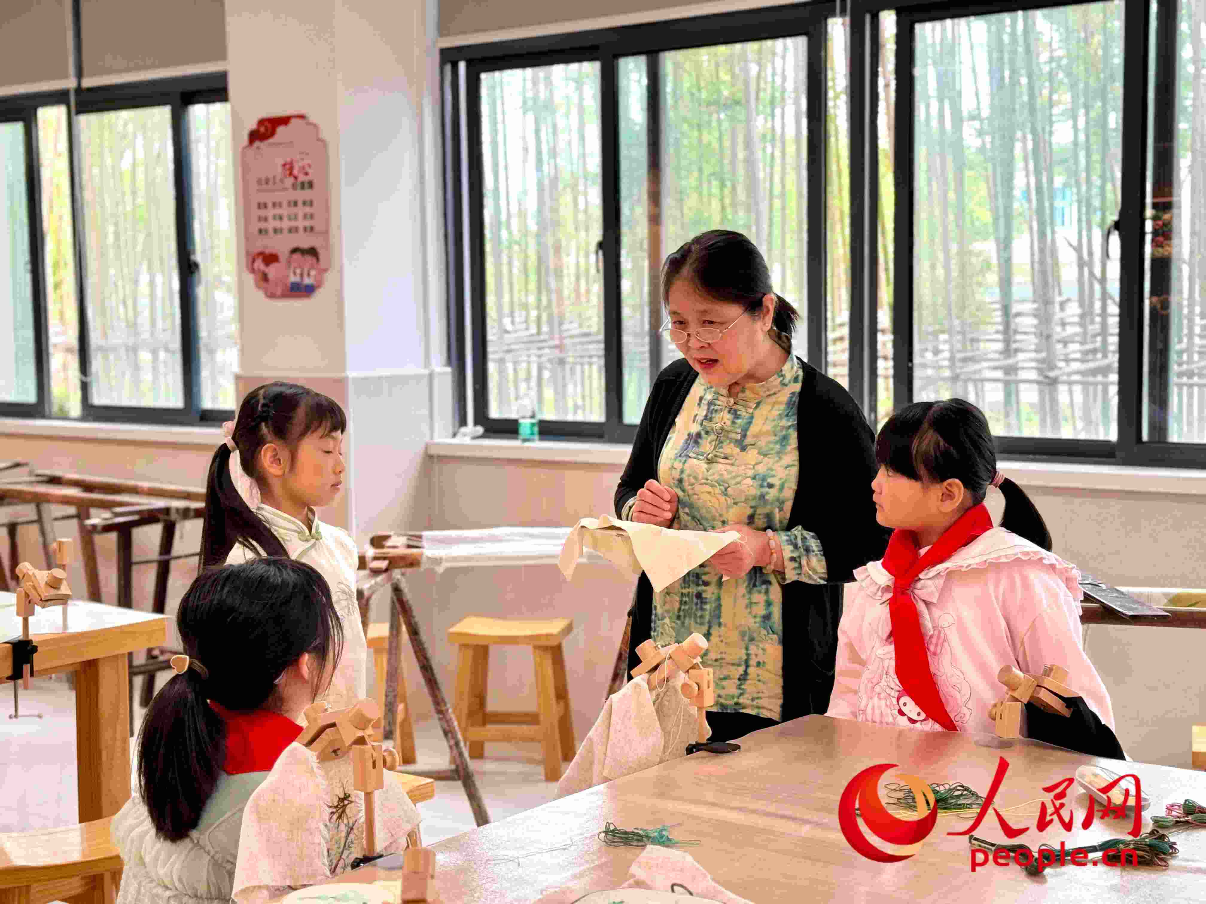 顧建珍（左三）在教孩子們刺繡知識(shí)。人民網(wǎng) 周靜圓攝