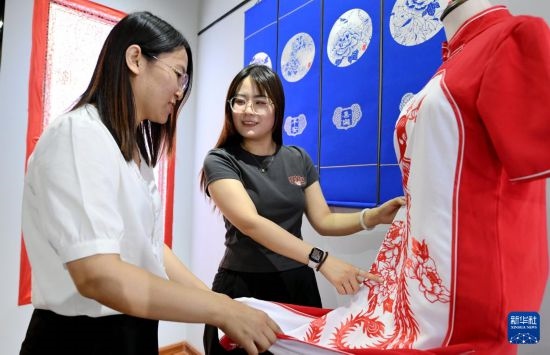 5月31日，在衡水市阜城縣一家剪紙工作室，游客在觀賞帶有剪紙元素的旗袍。