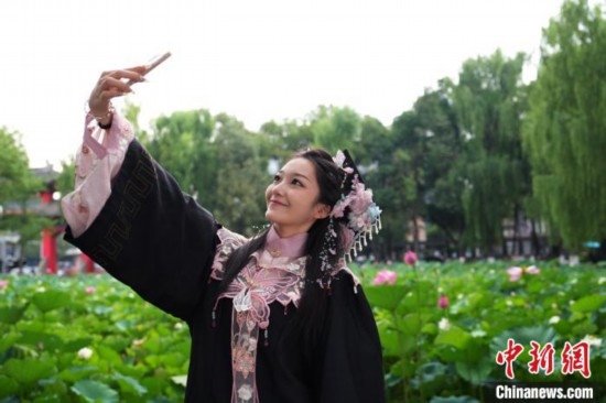 6月19日，時(shí)值一年畢業(yè)季，四川大學(xué)望江校區(qū)荷花池里的荷花盛開(kāi)，成為了畢業(yè)生們的打卡圣地，吸引了眾多畢業(yè)生拍照留念。圖為畢業(yè)生在荷花池邊拍照留念。中新社記者 安源 攝