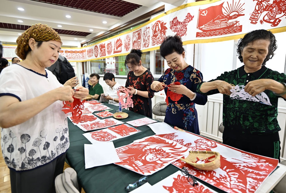 6月19日，長城花園社區(qū)居民在社區(qū)“才藝堂”制作剪紙。