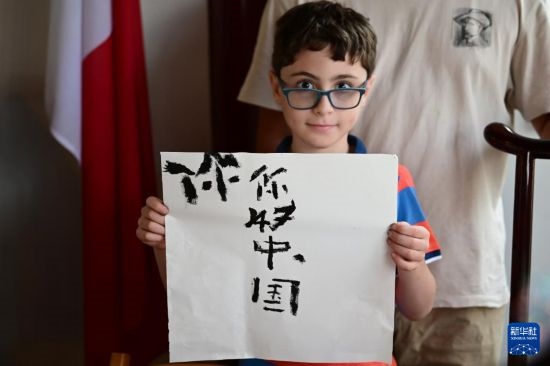 7月4日，在馬耳他桑塔露琪亞市的中國古典園林“靜園”，一名男孩展示他的書法作品。新華社發(fā)（喬納森·博格 攝）