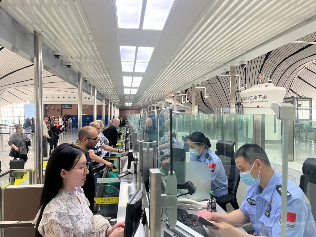 7月5日，北京大興國際機(jī)場邊檢站民警正在辦理邊檢查驗(yàn)手續(xù)。（北京大興國際機(jī)場邊檢站供圖）