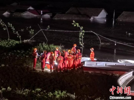  7月6日凌晨3時，在湖南岳陽華容縣團(tuán)洲垸洞庭湖一線堤防，救援人員剛剛完成一次救援任務(wù)，遠(yuǎn)處是被淹的民房。中新社記者 白祖偕 攝