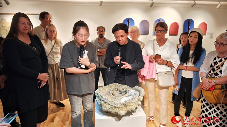 參展人、景德鎮(zhèn)陶瓷大學(xué)設(shè)計(jì)藝術(shù)學(xué)院副院長余劍峰（中）向來賓介紹參展作品。人民網(wǎng)記者 殷淼攝