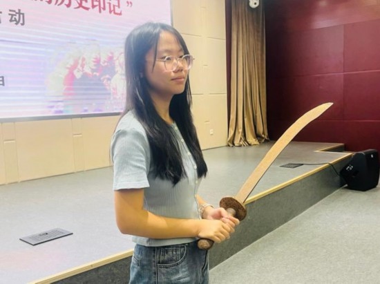 圖為南開大學(xué)社會(huì)實(shí)踐隊(duì)學(xué)生代表呼月紅在學(xué)術(shù)交流活動(dòng)現(xiàn)場(chǎng)，展示河間調(diào)研行中獲贈(zèng)的一戰(zhàn)華工蔡世春曾使用過的一把大刀。林卓瑋 攝