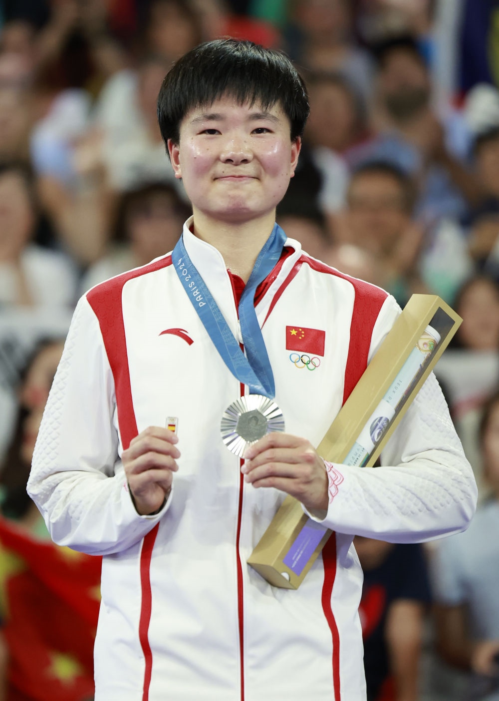 巴黎奧運(yùn)會(huì)羽毛球女子單打亞軍、中國(guó)選手何冰嬌在頒獎(jiǎng)儀式上一手握著銀牌，一手握著西班牙奧委會(huì)徽章（2024年8月5日攝）。新華社記者 任正來(lái) 攝