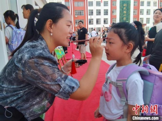 圖為衡水市利民路小學(xué)，老師為學(xué)生點(diǎn)朱砂痣，寓意開(kāi)啟智慧。張松 攝