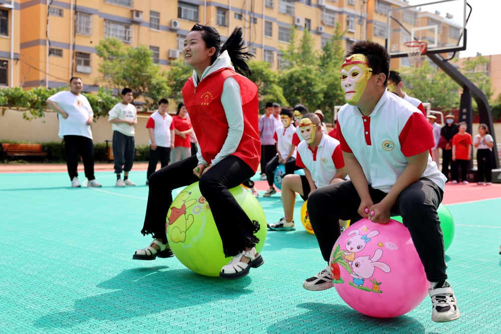 2024年5月17日，在山東省棗莊市市中區(qū)特殊教育中心，青年志愿者與智力障礙學(xué)生一起做游戲。新華社發(fā)（孫中喆攝）