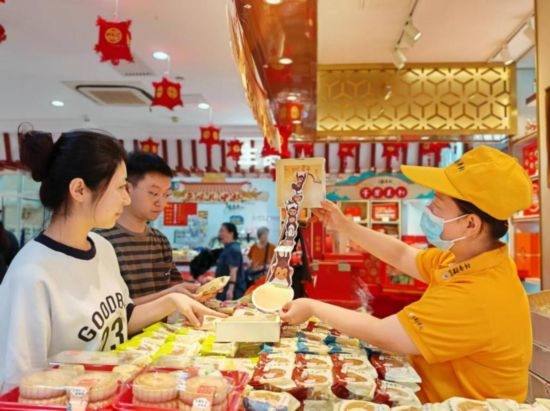 北京稻香村一家門店內(nèi)，售貨員向顧客展示新上市的月餅禮盒。（受訪者供圖）