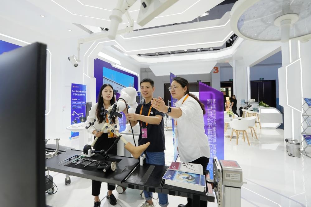 9月11日，一位媒體記者（中）在2024年服貿(mào)會(huì)國(guó)家會(huì)議中心會(huì)場(chǎng)體驗(yàn)北京納通科技集團(tuán)有限公司的膝關(guān)節(jié)置換手術(shù)機(jī)器人。新華社記者鞠煥宗 攝