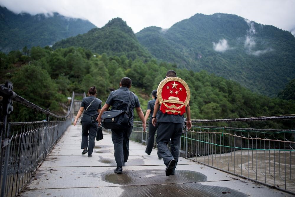 云南省怒江傈僳族自治州貢山縣人民法院法官鄧興背著國徽與同事們跨過怒江（2019年8月30日攝）。怒江高山峽谷眾多，交通不便，為方便群眾、更好地開展法律服務(wù)，背著國徽攀高山、過索橋、躲落石、鉆老林……成為鄧興法官的工作常態(tài)。新華社記者 江文耀 攝
