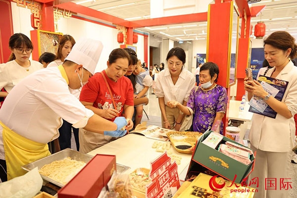 演出前，在天津桂發(fā)祥十八街麻花制作技藝非遺體驗展臺前，泰國民眾體驗天津麻花制作。人民網(wǎng)記者 楊一攝