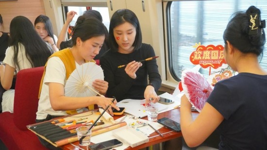 10月1日，旅客們?cè)贕1634次列車上給油紙傘作畫。新華社記者周義 攝