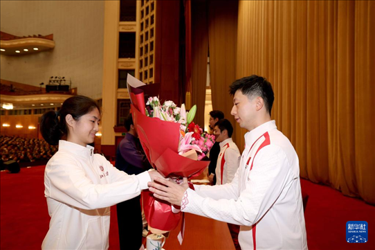 11月15日，一名學(xué)生代表在報(bào)告會(huì)上向乒乓球運(yùn)動(dòng)員馬龍（右）獻(xiàn)花。新華社記者 李明 攝