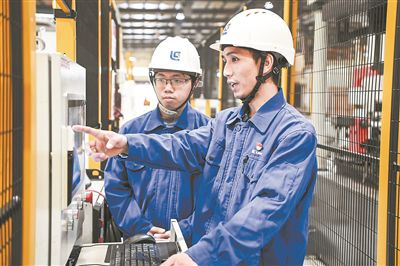 在廣西柳工機械股份有限公司生產(chǎn)車間內(nèi)，一名高級技師（右）給徒弟講解數(shù)控設(shè)備操作細節(jié)。新華社記者 曹祎銘攝