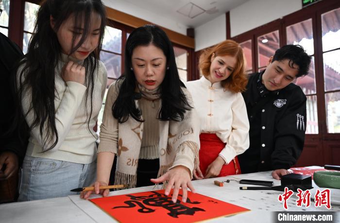 1月20日，西泠印社社員李硯（左二）為外籍留學(xué)生講述蛇年福字貼創(chuàng)作靈感。當(dāng)日，來自巴西、馬來西亞、加納、哈薩克斯坦的外籍留學(xué)生在浙江杭州西泠印社體驗(yàn)福貼、春聯(lián)和篆刻，感受古老的中國傳統(tǒng)文化。中新社記者 王剛 攝