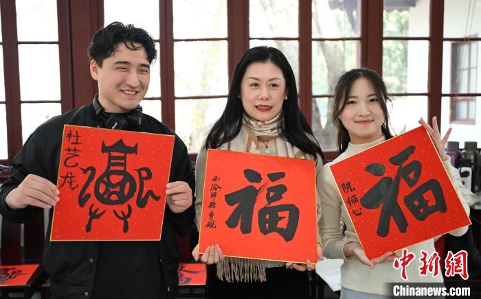 1月20日，外籍留學(xué)生和西泠印社社員李硯(中)展示各自創(chuàng)作的福貼。當(dāng)日，來自巴西、馬來西亞、加納、哈薩克斯坦的外籍留學(xué)生在浙江杭州西泠印社體驗(yàn)福貼、春聯(lián)和篆刻，感受古老的中國傳統(tǒng)文化。中新社記者 王剛 攝